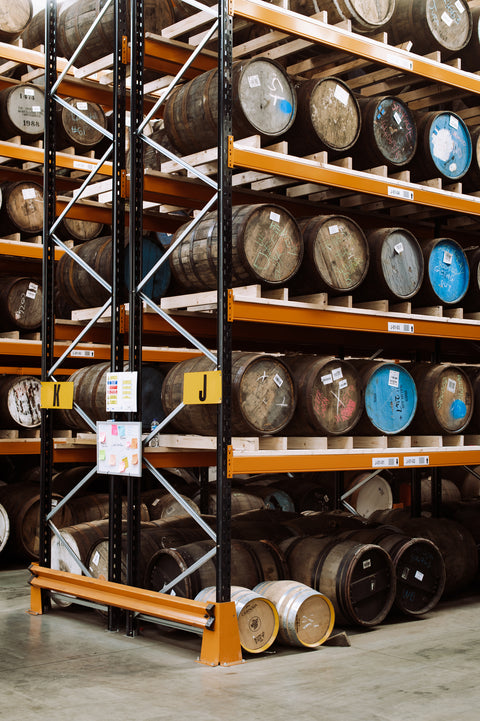A warehouse racking with wooden casks of various sizes on it