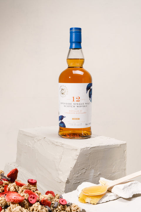 A bottle of Ferg and Harris 12-year-old Linkwood, on top of clay block. A spoon of runny honey on one side and toasted oats mixed with red berries on the other