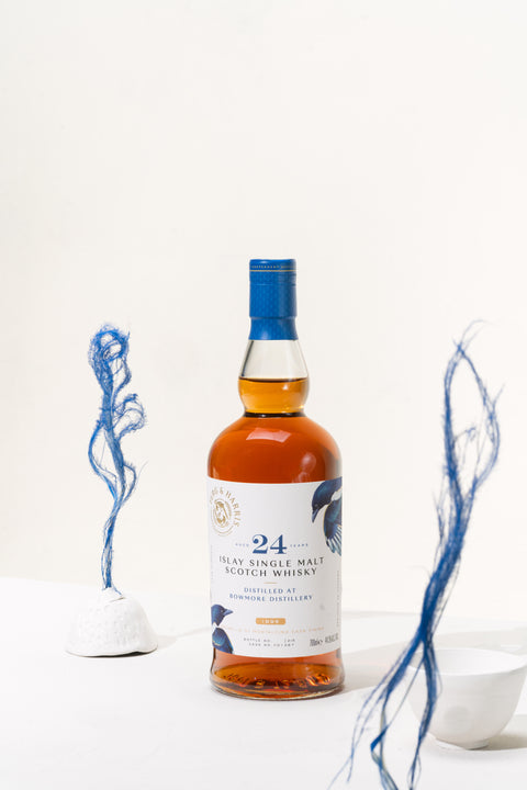 A bottle of Ferg and Harris 24-year-old Bowmore, white ceramic bowls and blue painted dried grass coming from them